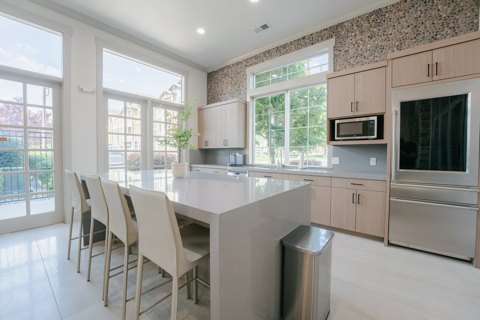 Aldara clubhouse kitchen with an island, pale wood cabinetry and garden views