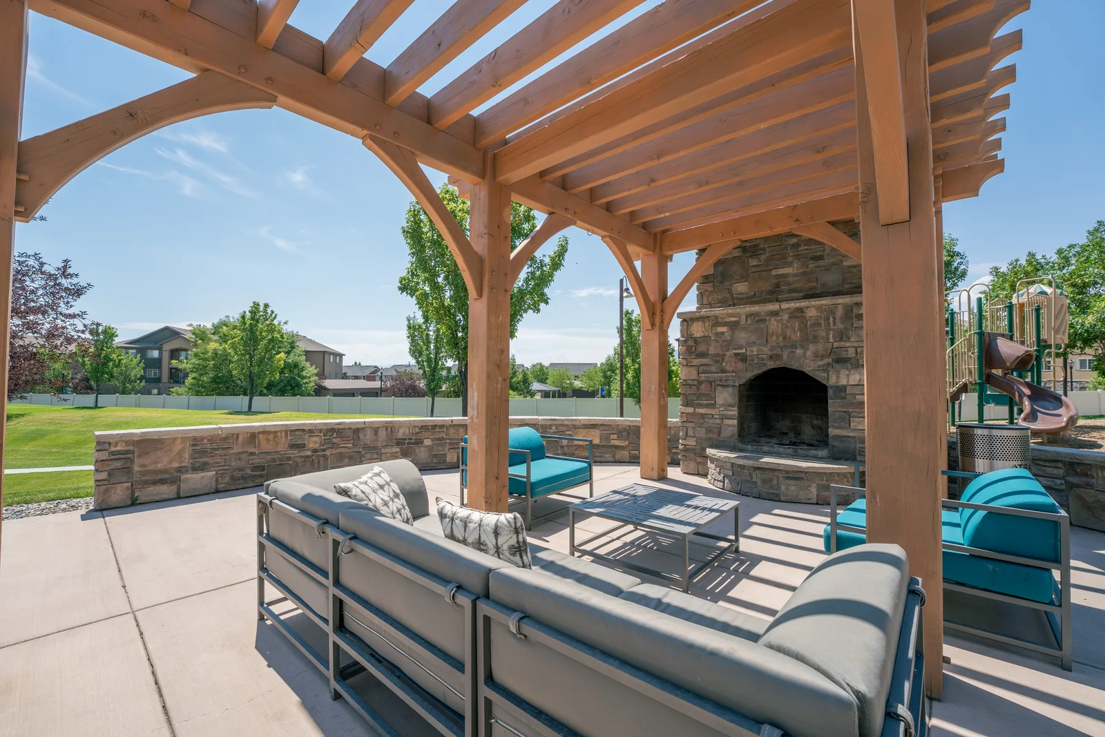 Aldara outdoor lounge beneath a timber pergola beside a stone fireplace