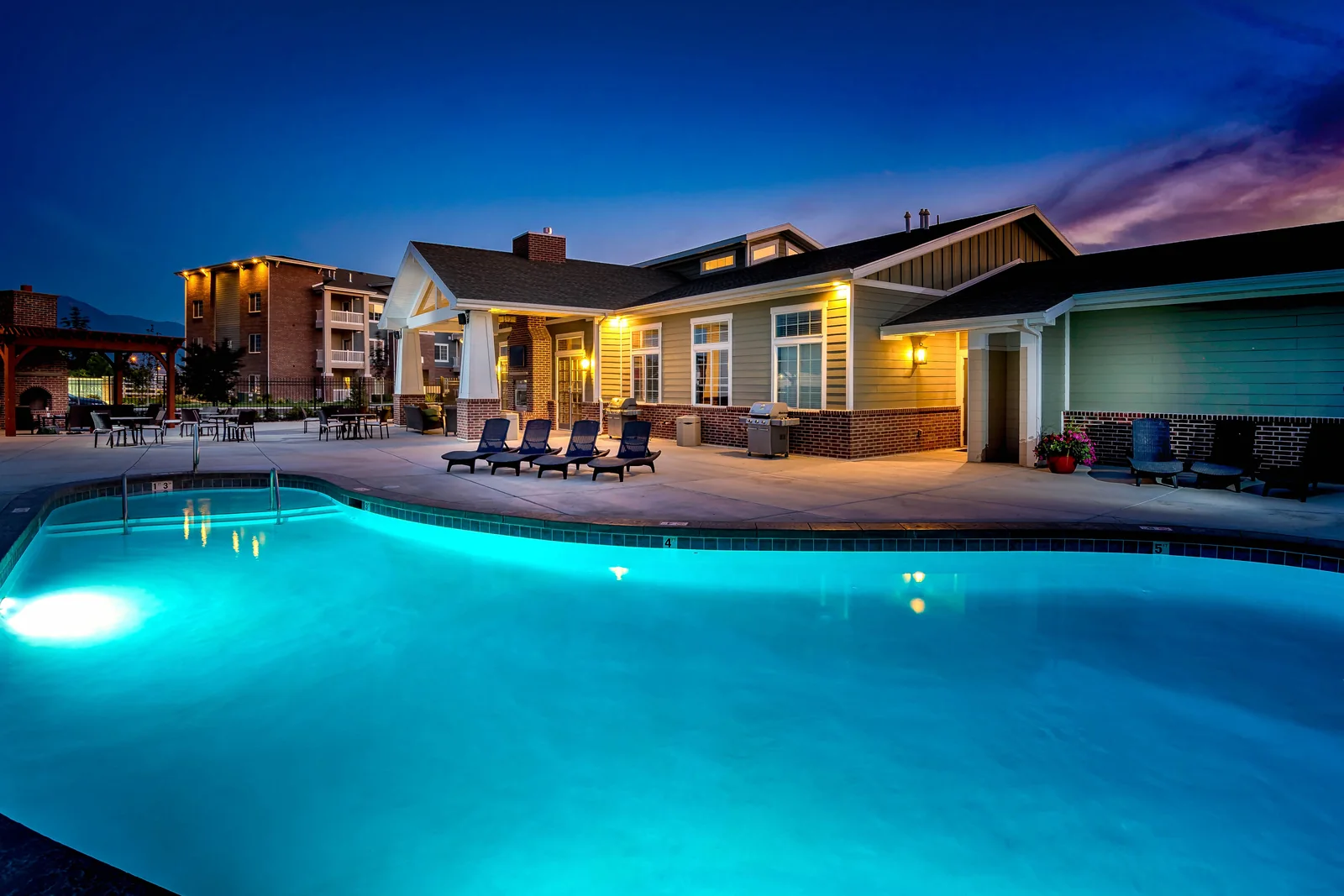The illuminated pool and clubhouse at Outlook at twilight